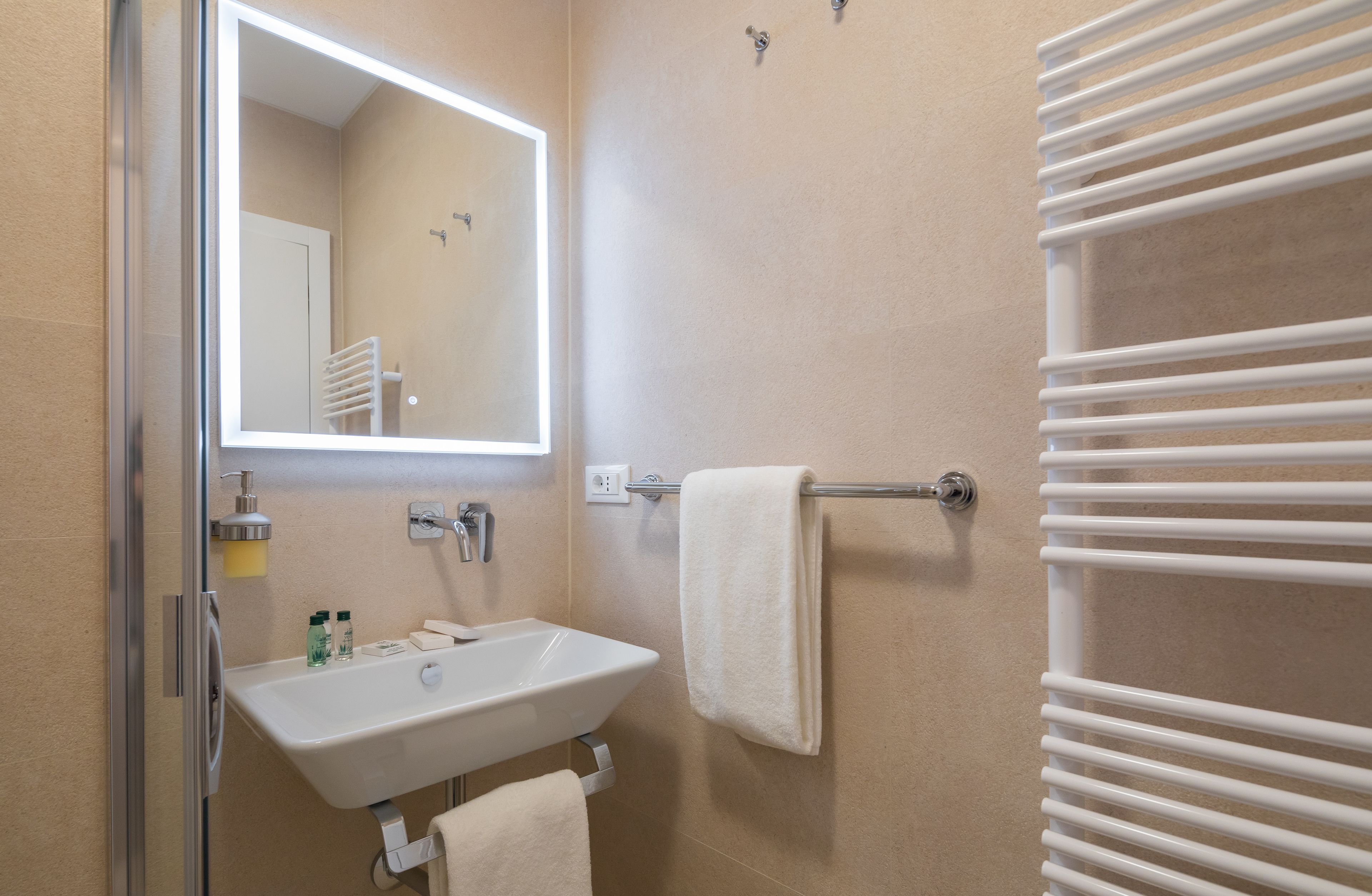Een badkamer met een witte wastafel, spiegel, handdoekhouder en een handdoek aan de houder.