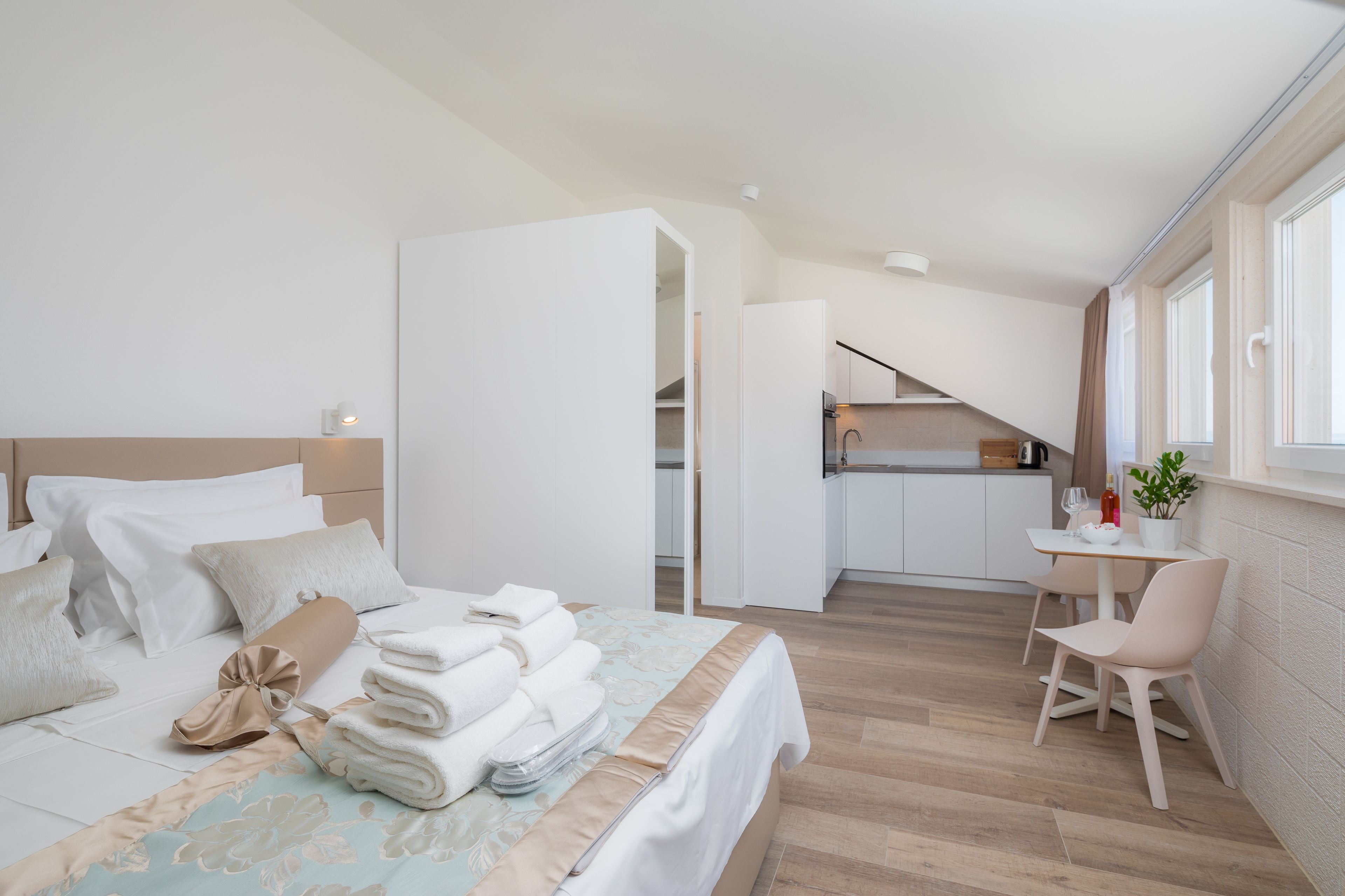 Una habitación de hotel moderna con una cama bien hecha, un pequeño comedor y vistas a la cocina.