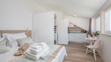 Una habitación de hotel moderna con una cama bien hecha, un pequeño comedor y vistas a la cocina.