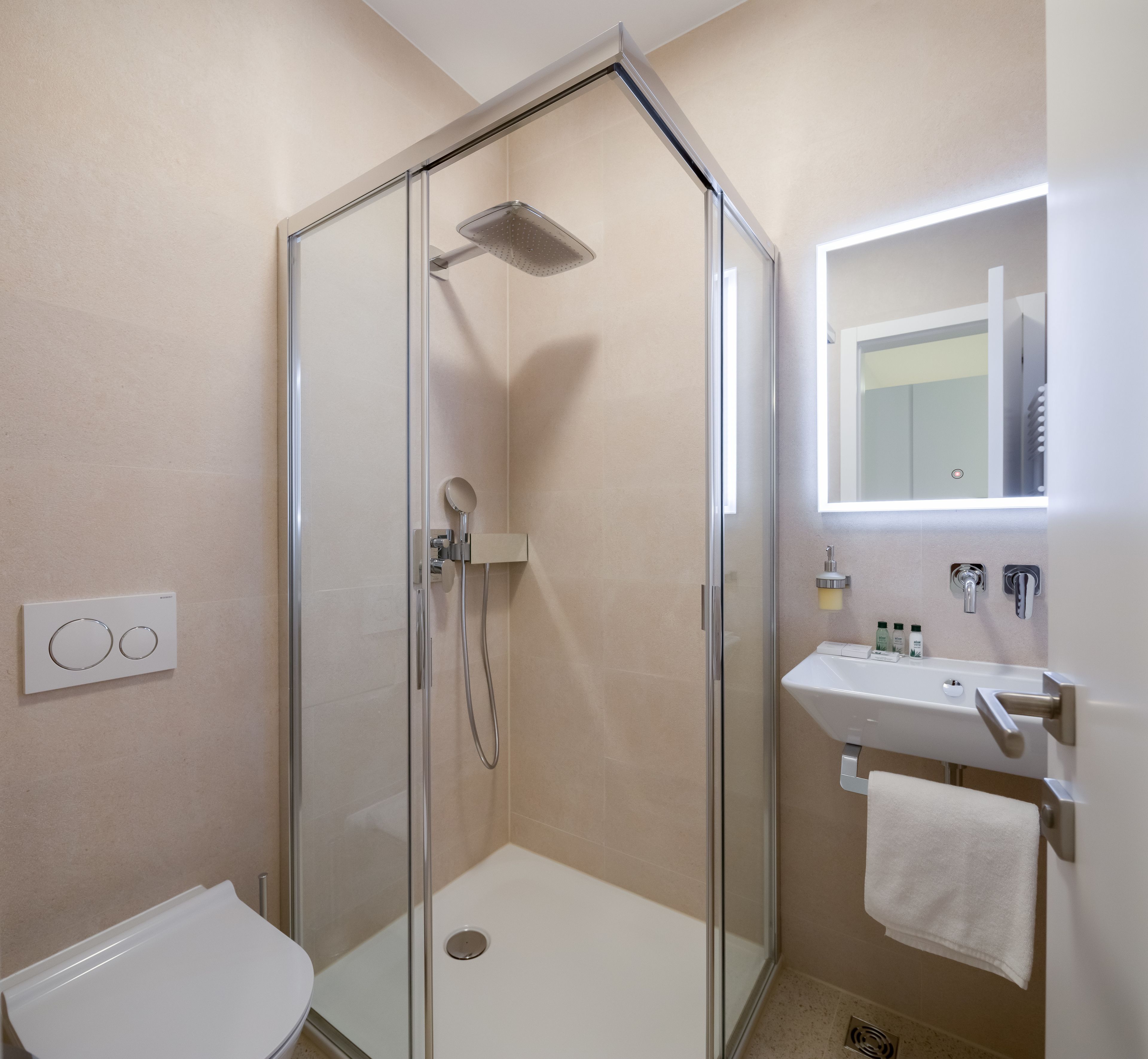 Ein modernes Badezimmer mit einer Duschkabine aus Glas, einem weißen Waschbecken und einem Spiegel darüber.