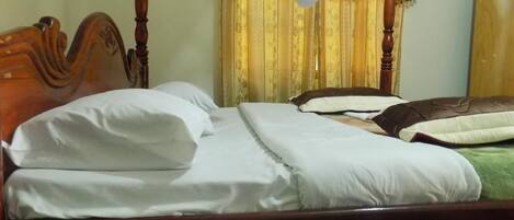 A neatly made bed with white linens and a wooden headboard.
