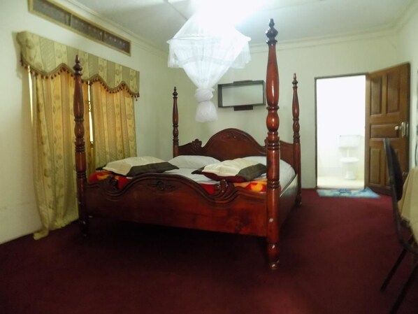 Un dormitorio con cama con dosel, televisor en la pared y puerta que da a otra habitación.