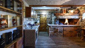 Eine rustikale Küche mit Steinwand, Holzschränken und Kamin aus Backsteinen.