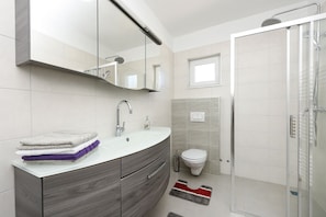 A modern bathroom with a vanity, sink, and shower.