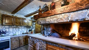 Eine rustikale Küche mit Steinwänden, Holzschränken und einem Kamin.