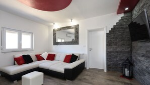 Ein modernes Wohnzimmer mit Ecksofa, einer Wand aus Stein und einer Treppe.