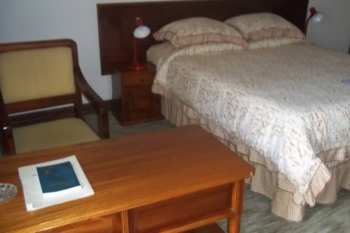Une chambre à coucher avec un lit, des tables de chevet, un bureau et une chaise.