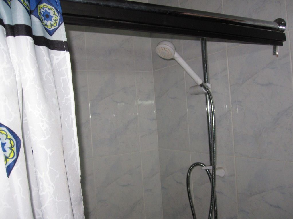 A shower with a handheld showerhead and a wall-mounted faucet.