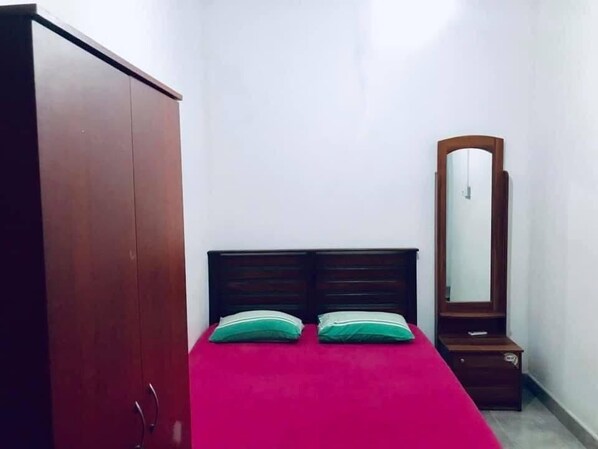 A bedroom with a bed, a wardrobe, and a mirror.