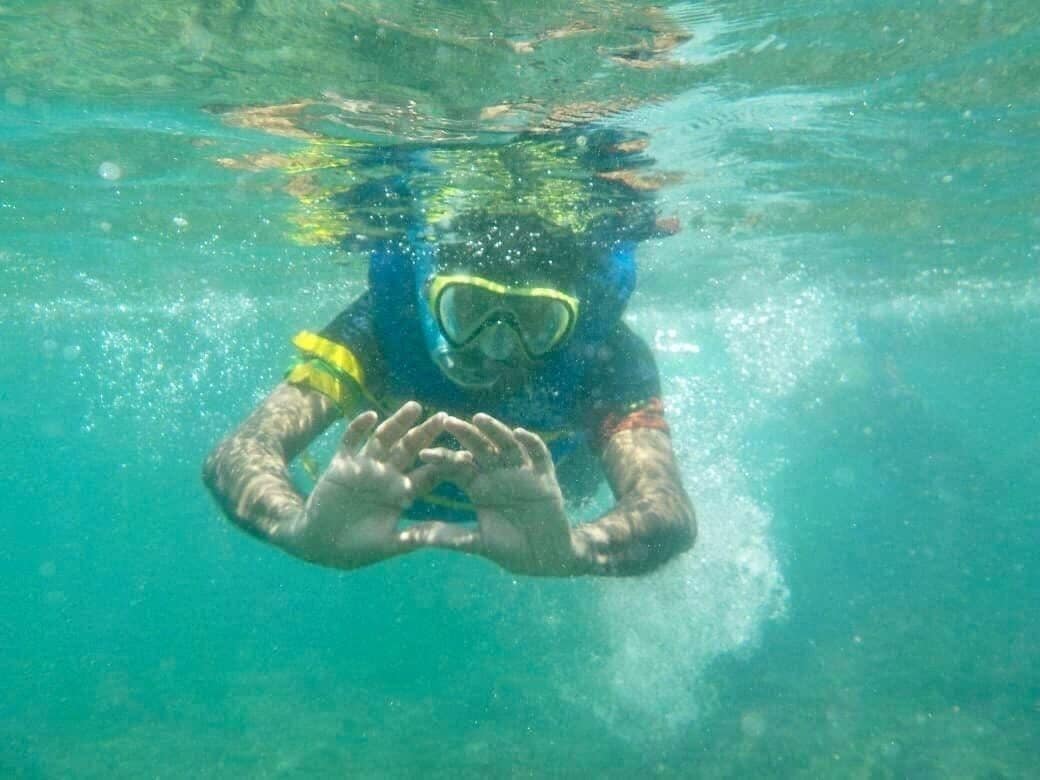 A person underwater, wearing a snorkel mask and fins.