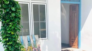 A house with a white exterior, a wooden door with a blue frame, and a window with white shutters.