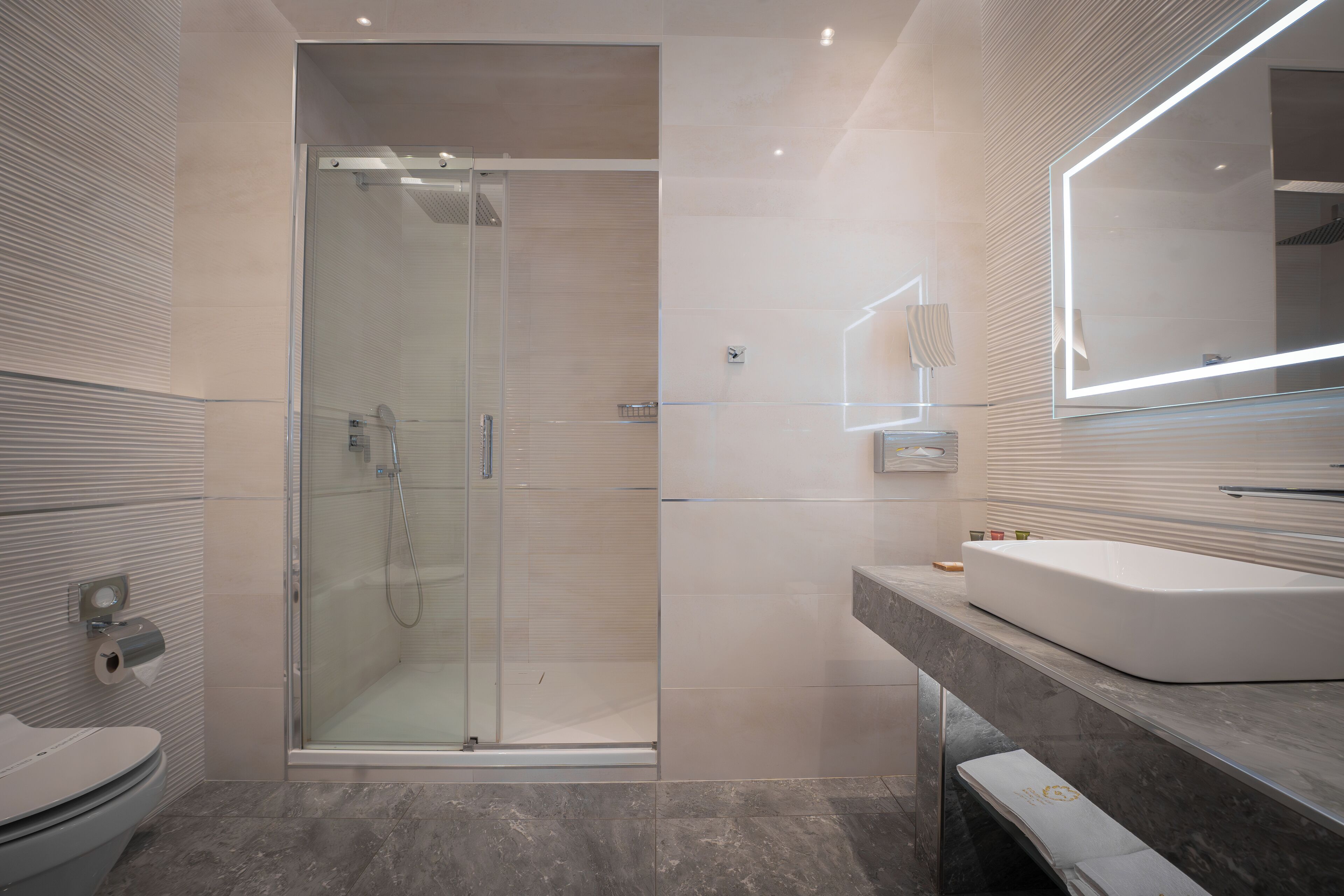 A modern bathroom with a glass-enclosed shower, a white sink, and a large mirror.