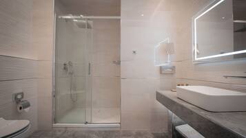 A modern bathroom with a glass-enclosed shower, a white sink, and a large mirror.