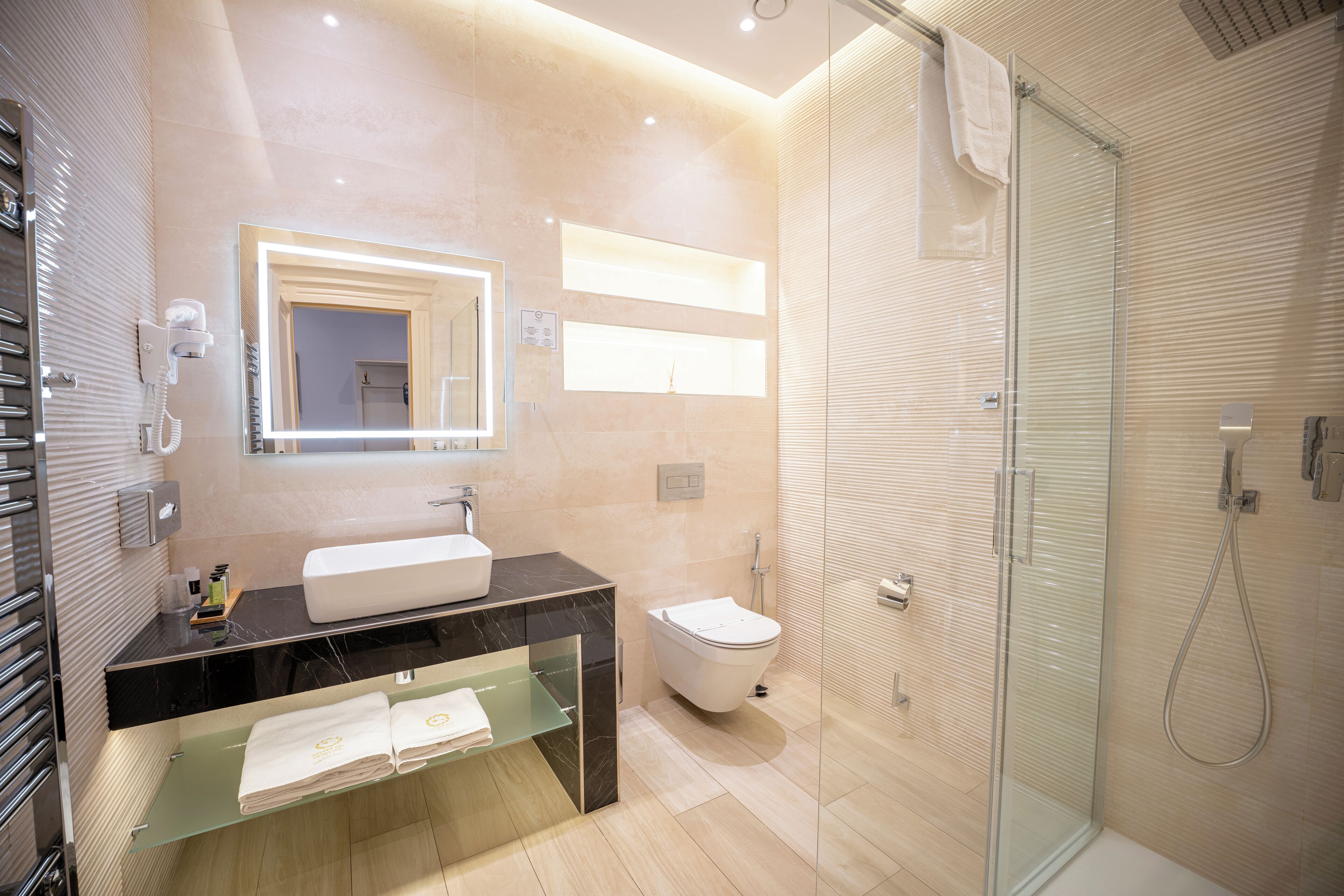 Een moderne badkamer met een douchecabine van glas, een wastafelmeubel met een wastafel en een toilet.