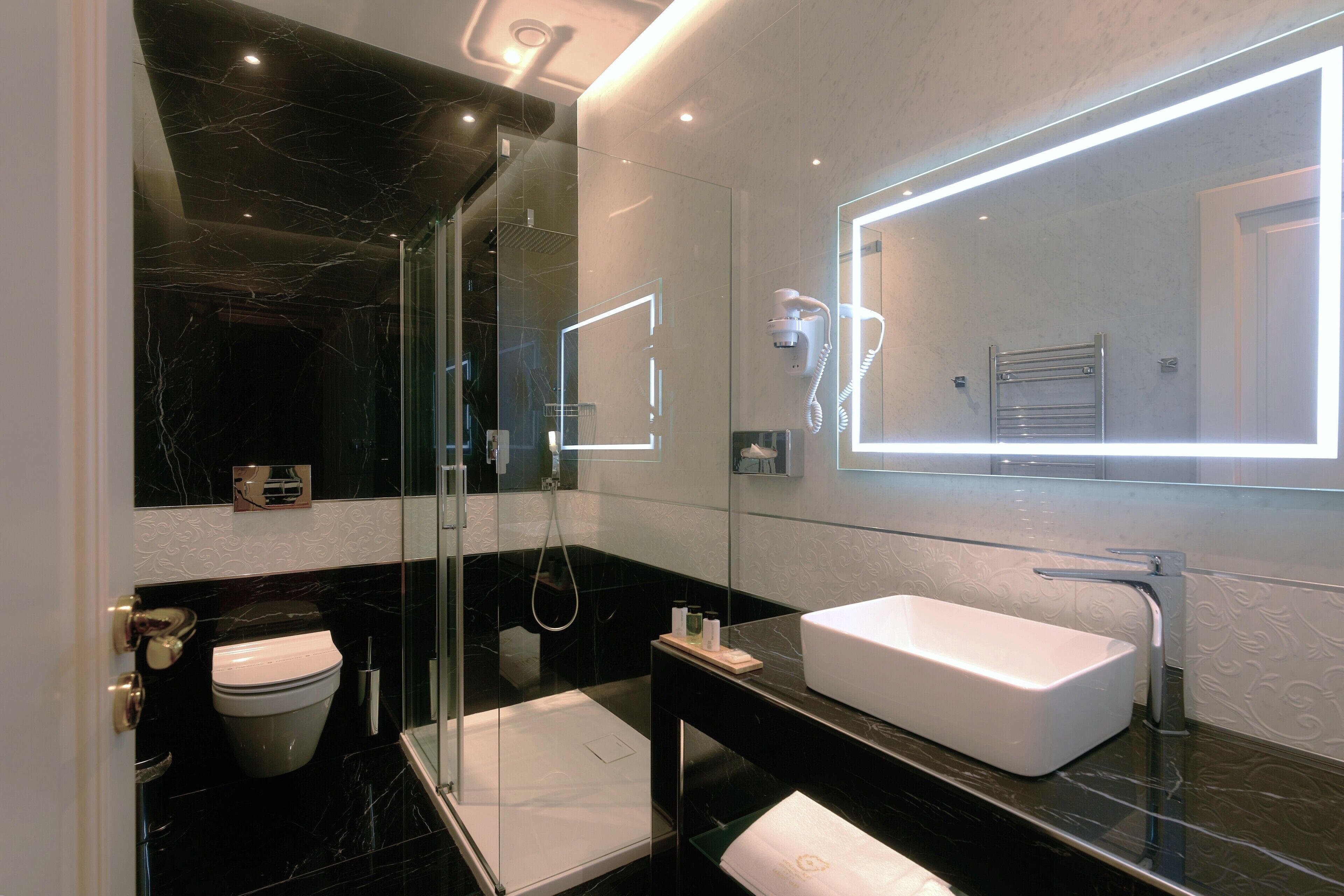 Un baño moderno con ducha envuelta en vidrio, un lavabo blanco y un espejo grande.