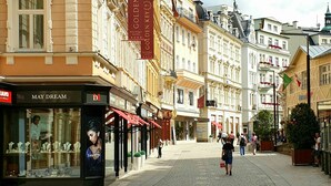 Una calle adoquinada flanqueada por edificios históricos, incluyendo un hotel boutique llamado 'Golden Key' y una tienda llamada 'May Dream'.