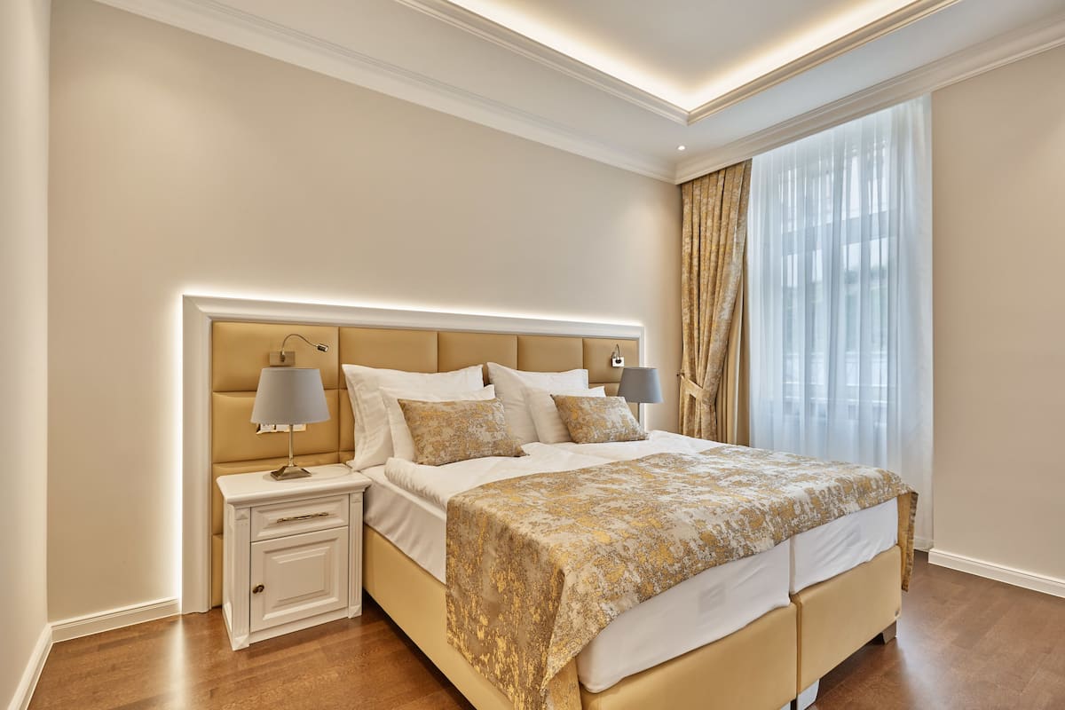 Una habitación de hotel con una cama grande, mesitas de noche y una ventana con cortinas.