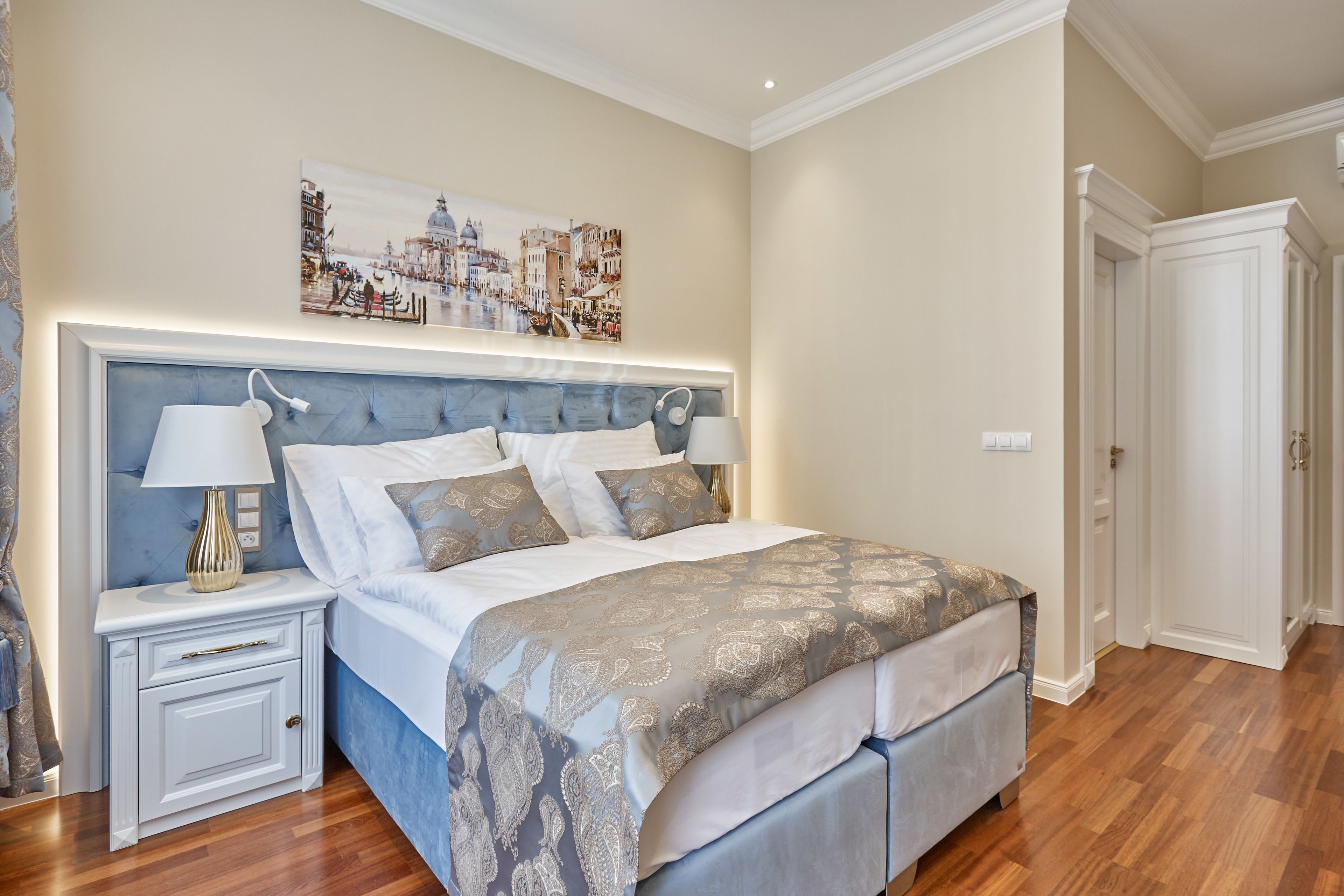 A bedroom with a bed, nightstands, and a painting on the wall.