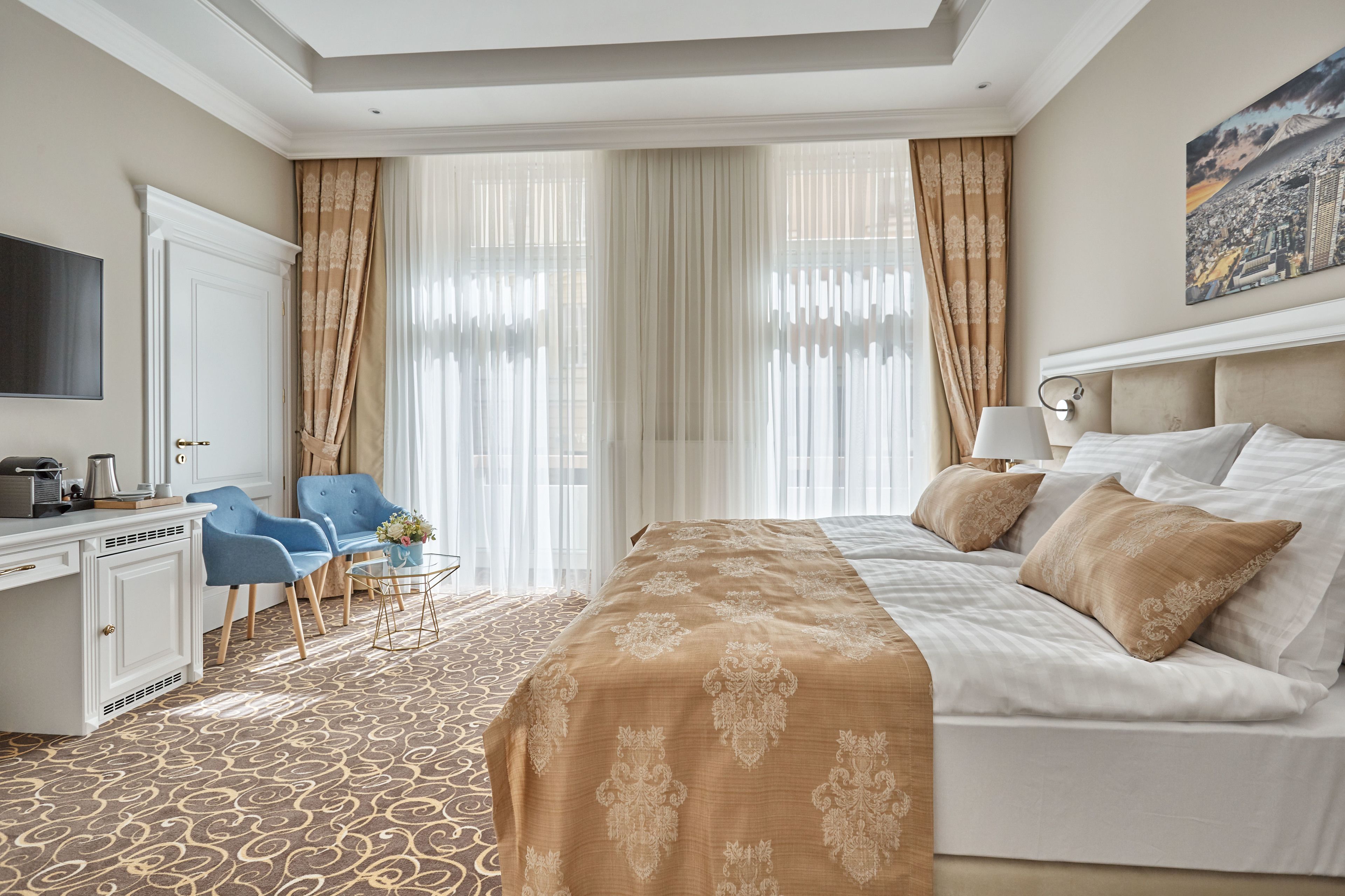 Habitación de hotel con una cama grande, un escritorio con computadora, una silla y un televisor.