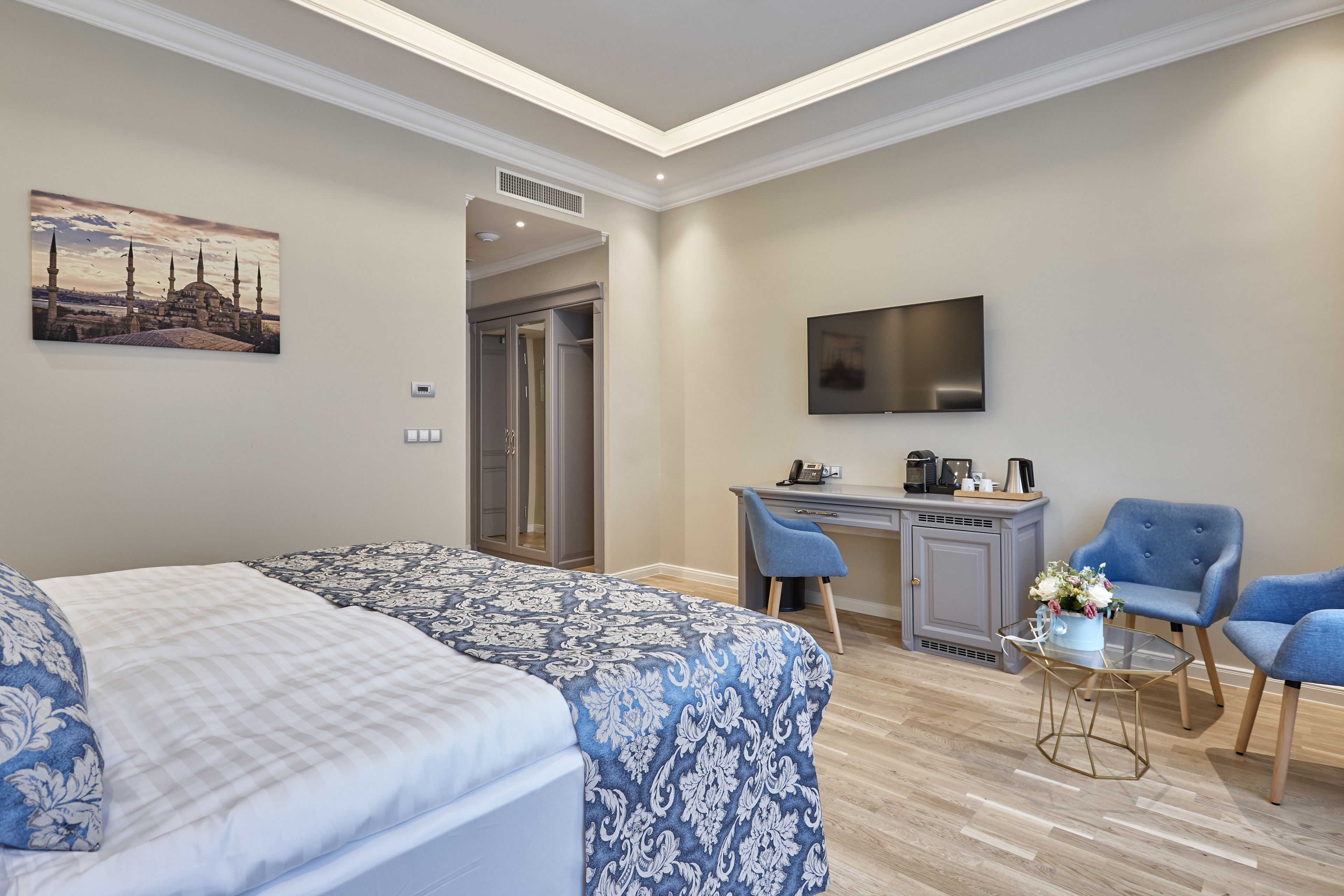 Een hotelkamer met een bed, een bureau, een stoel, een televisie en een schilderij aan de muur.