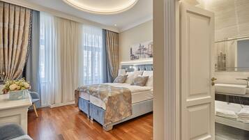 A bedroom with a large bed, a bedside table with a vase of flowers, and a view of the bathroom through an open door.