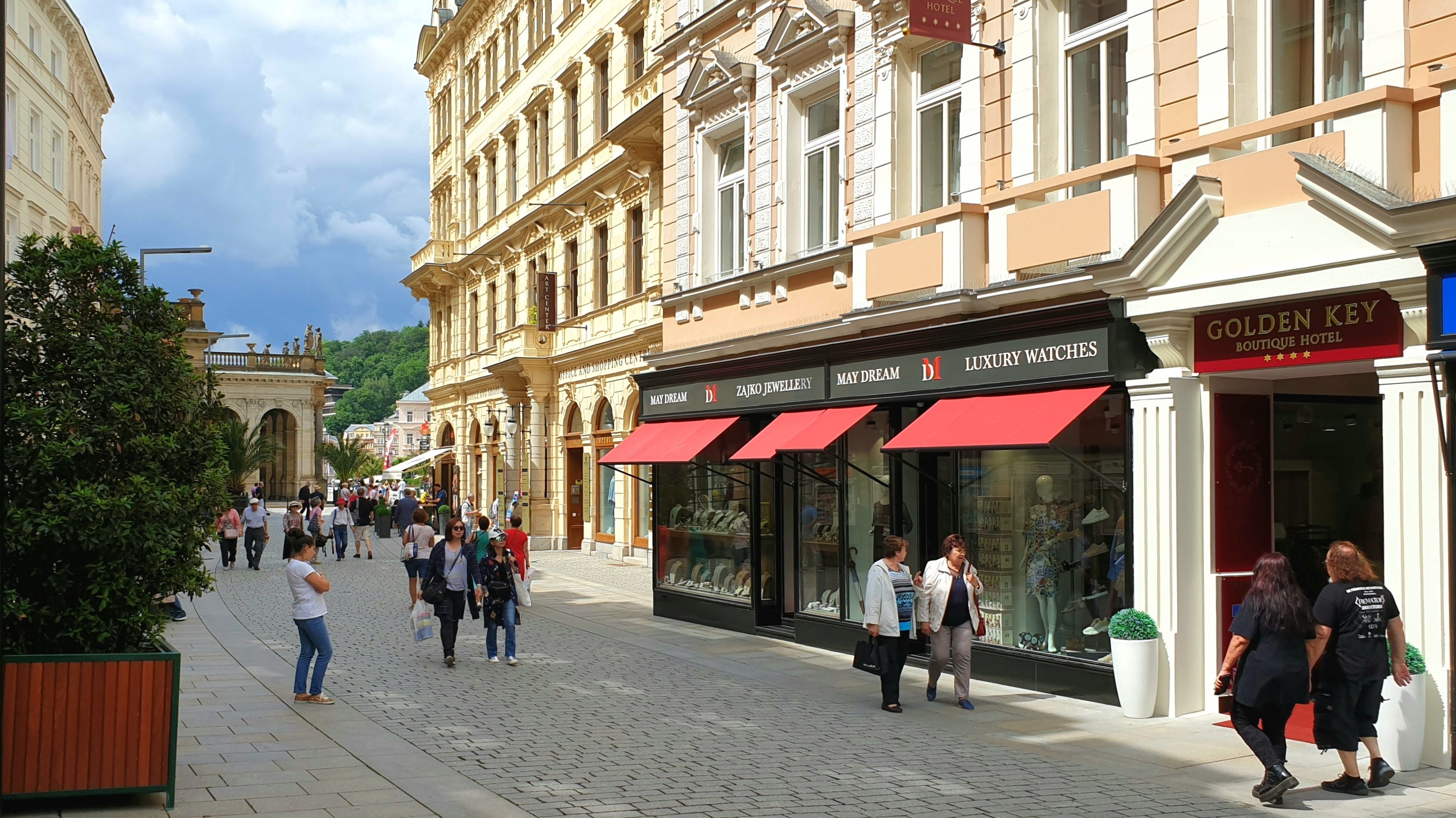 A cobblestone street lined with historic buildings, including a boutique hotel and a jewelry store.