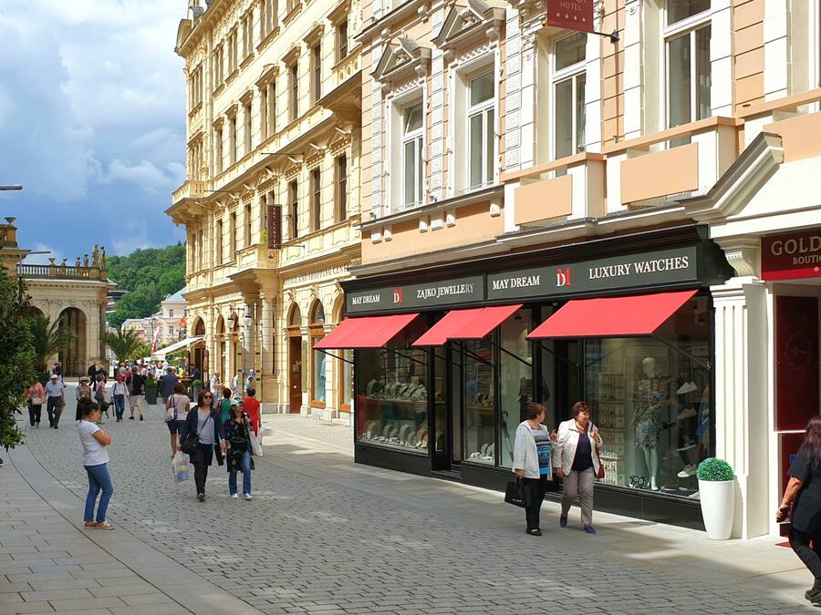 A cobblestone street lined with historic buildings, including a boutique hotel and a jewelry store.