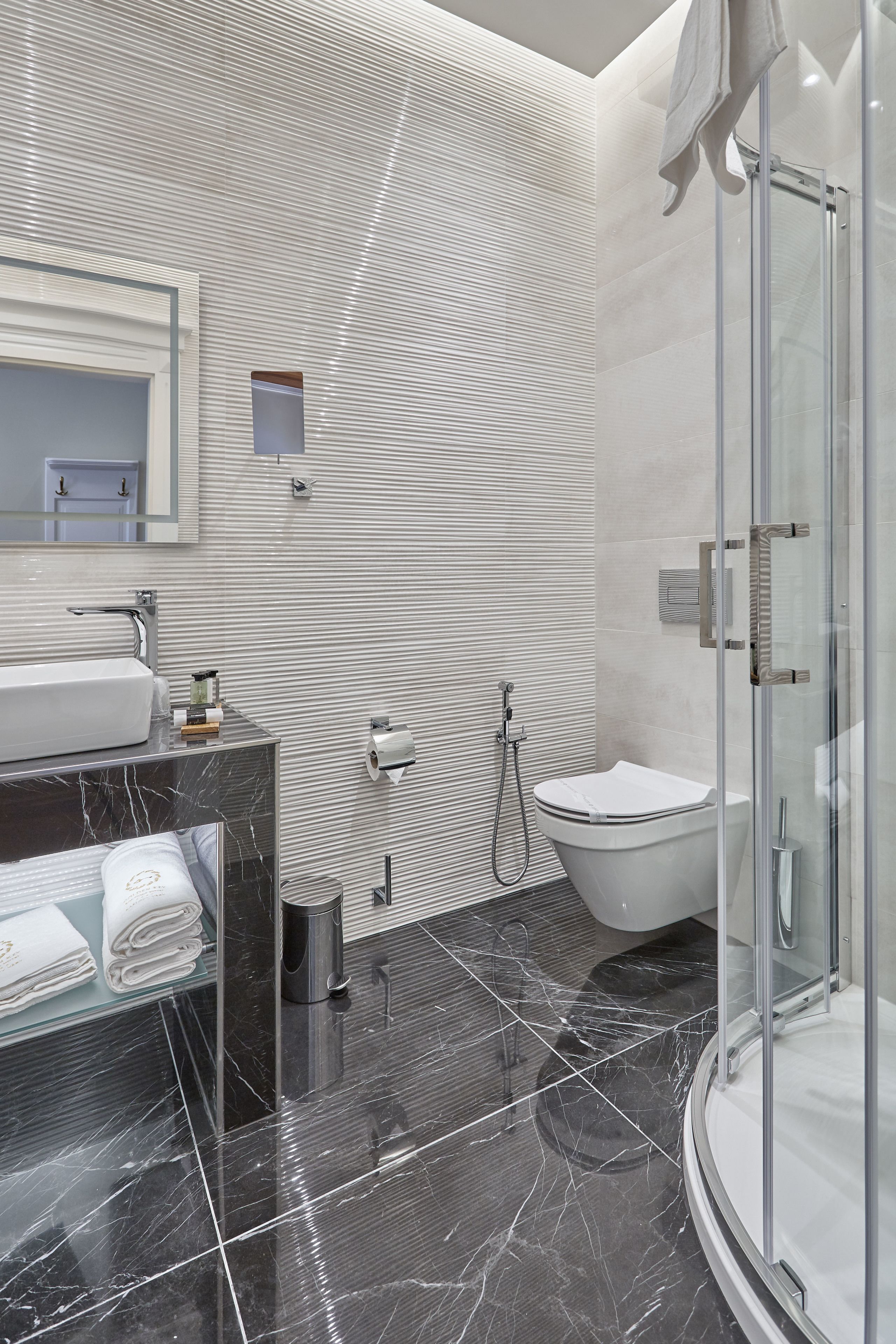 A modern bathroom with a glass-enclosed shower, a marble sink, and a toilet.
