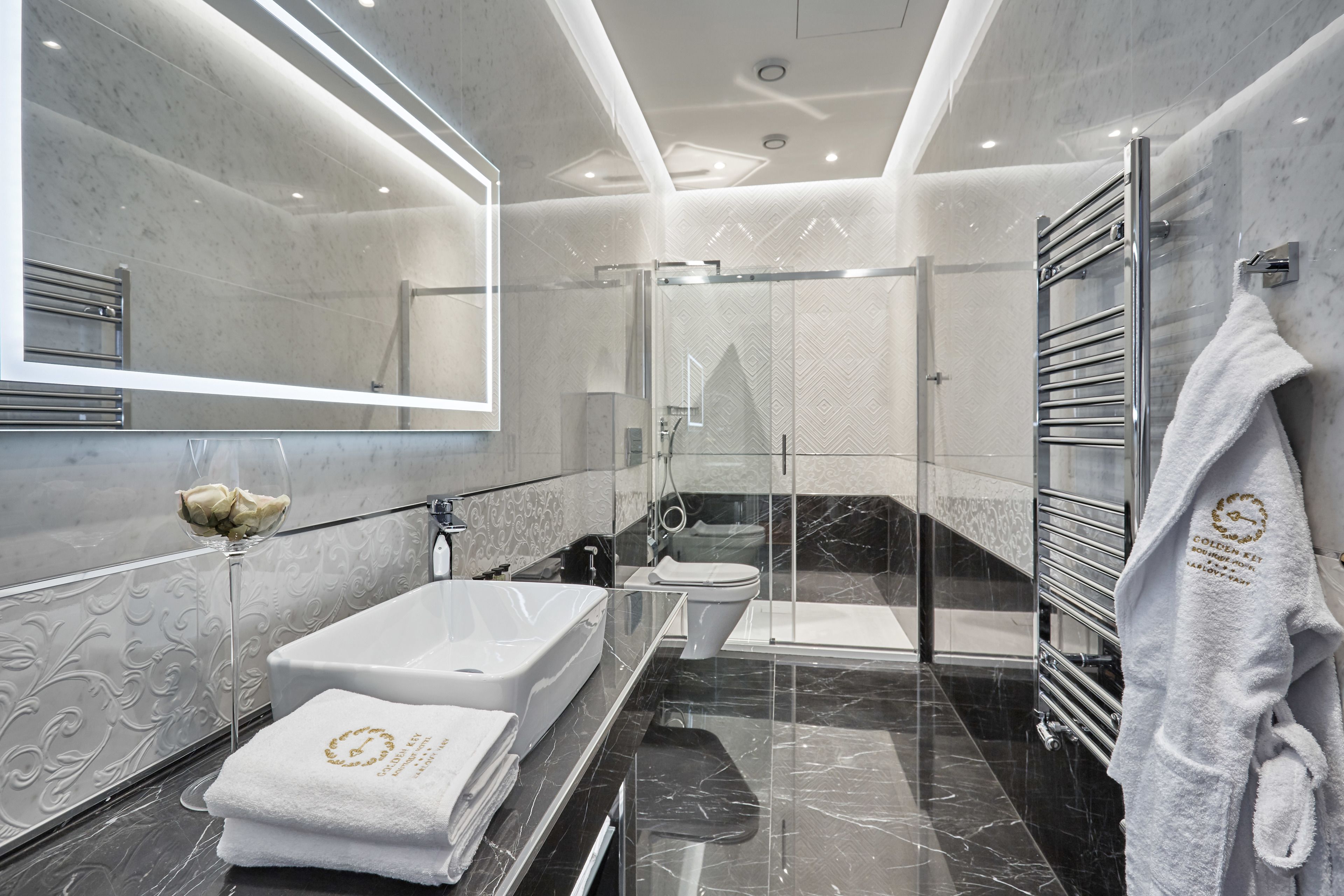 Un baño moderno con ducha de vidrio, una bañera blanca grande y un lavamanos independiente.