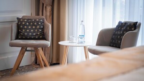 Una habitación de hotel con dos sillones, una mesita redonda y una cama.