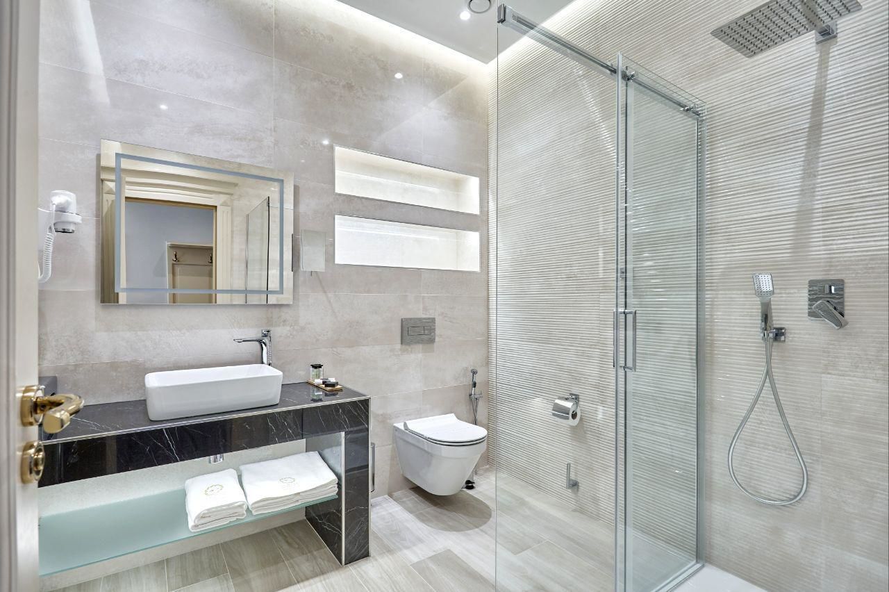 A modern bathroom with a glass-enclosed shower, a white sink, and a marble vanity.