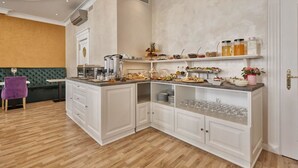 Una cocina moderna con armarios blancos, una isla integrada y diferentes productos para el desayuno exhibidos en estantes.