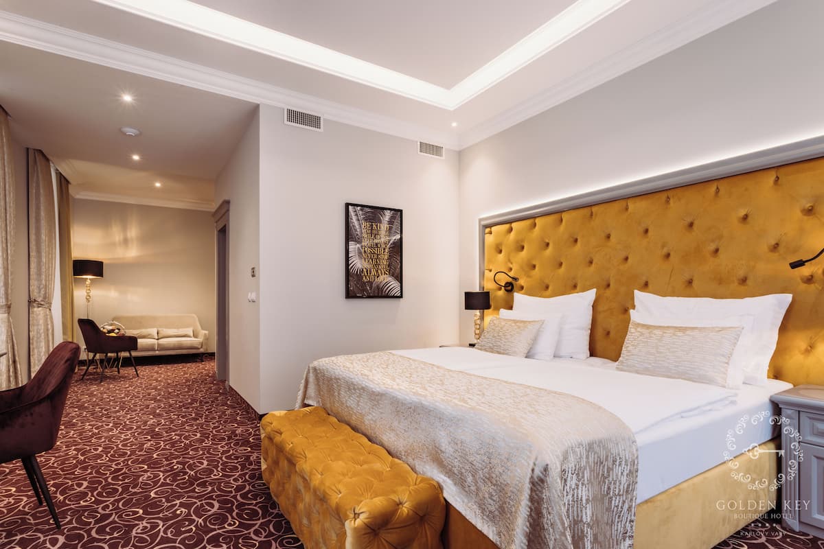 Una habitación de hotel con una cama grande, un banco, un sofá y un comedor.