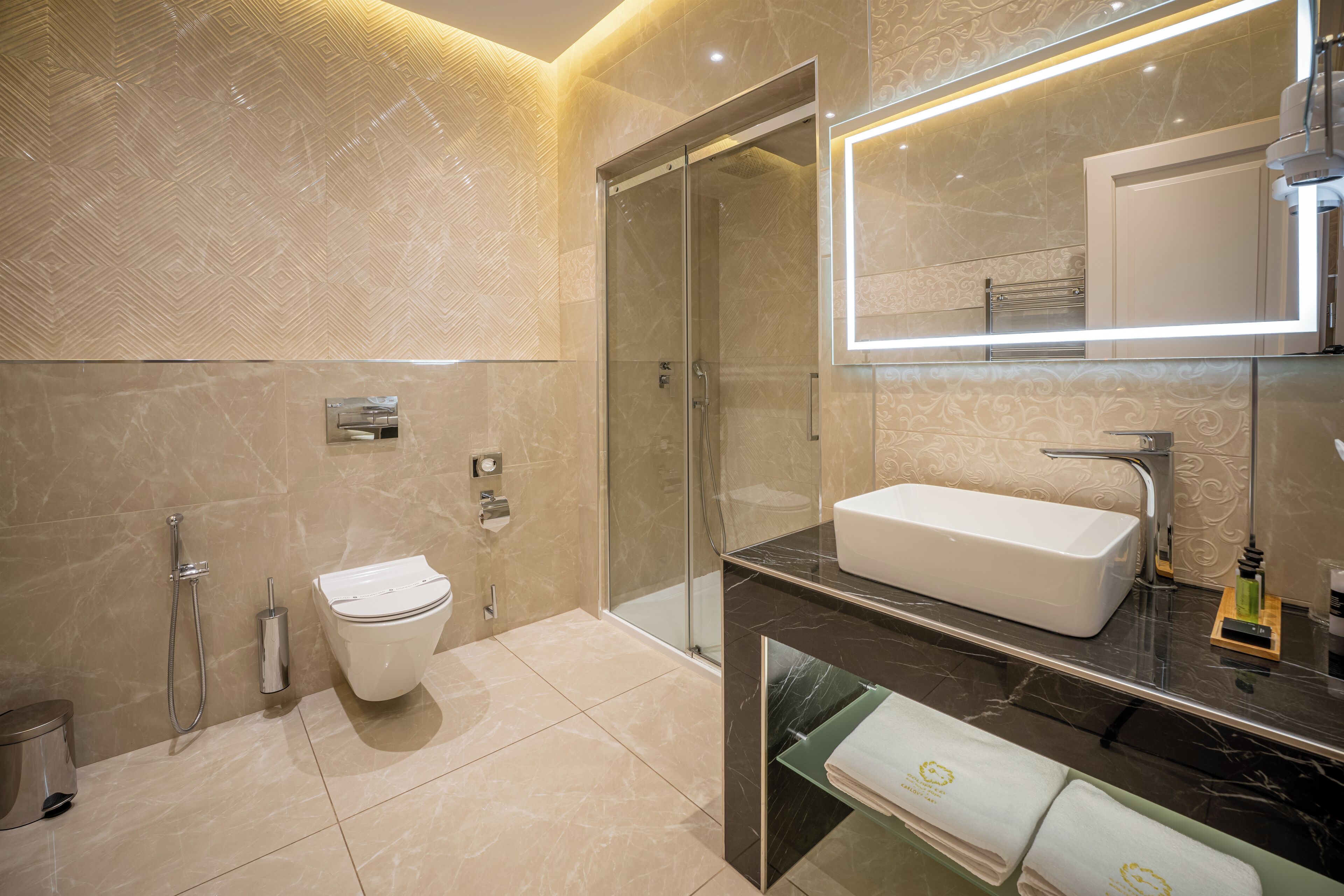 Un baño moderno con ducha de vidrio, lavamanos blanco y un espejo grande.