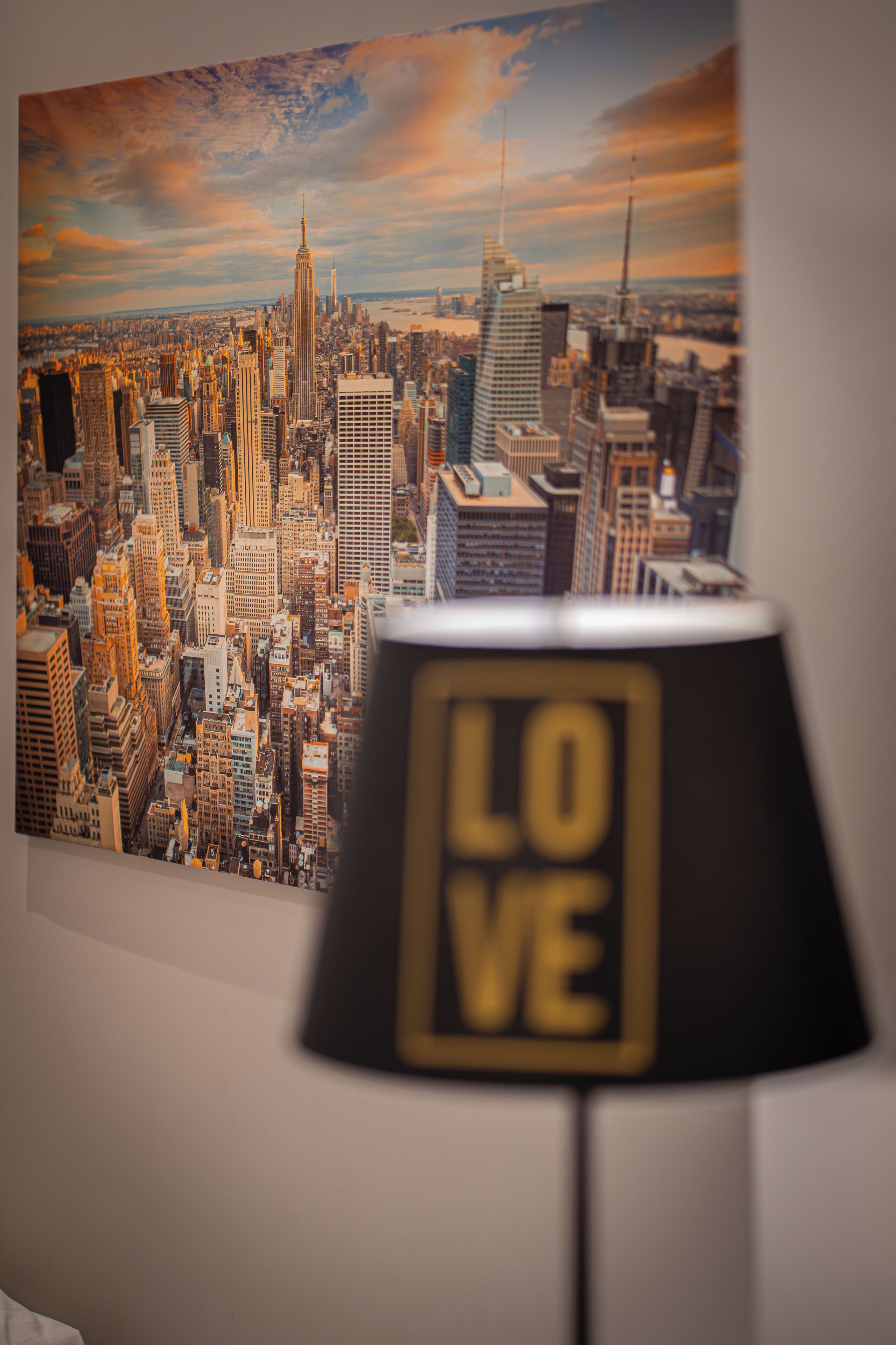 A cityscape view through a window, with a lamp displaying the word "LOVE" in the foreground.