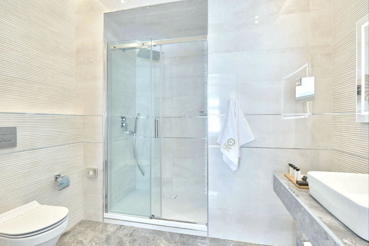 A modern bathroom with a glass-enclosed shower, a toilet, and a vanity with a bathtub.
