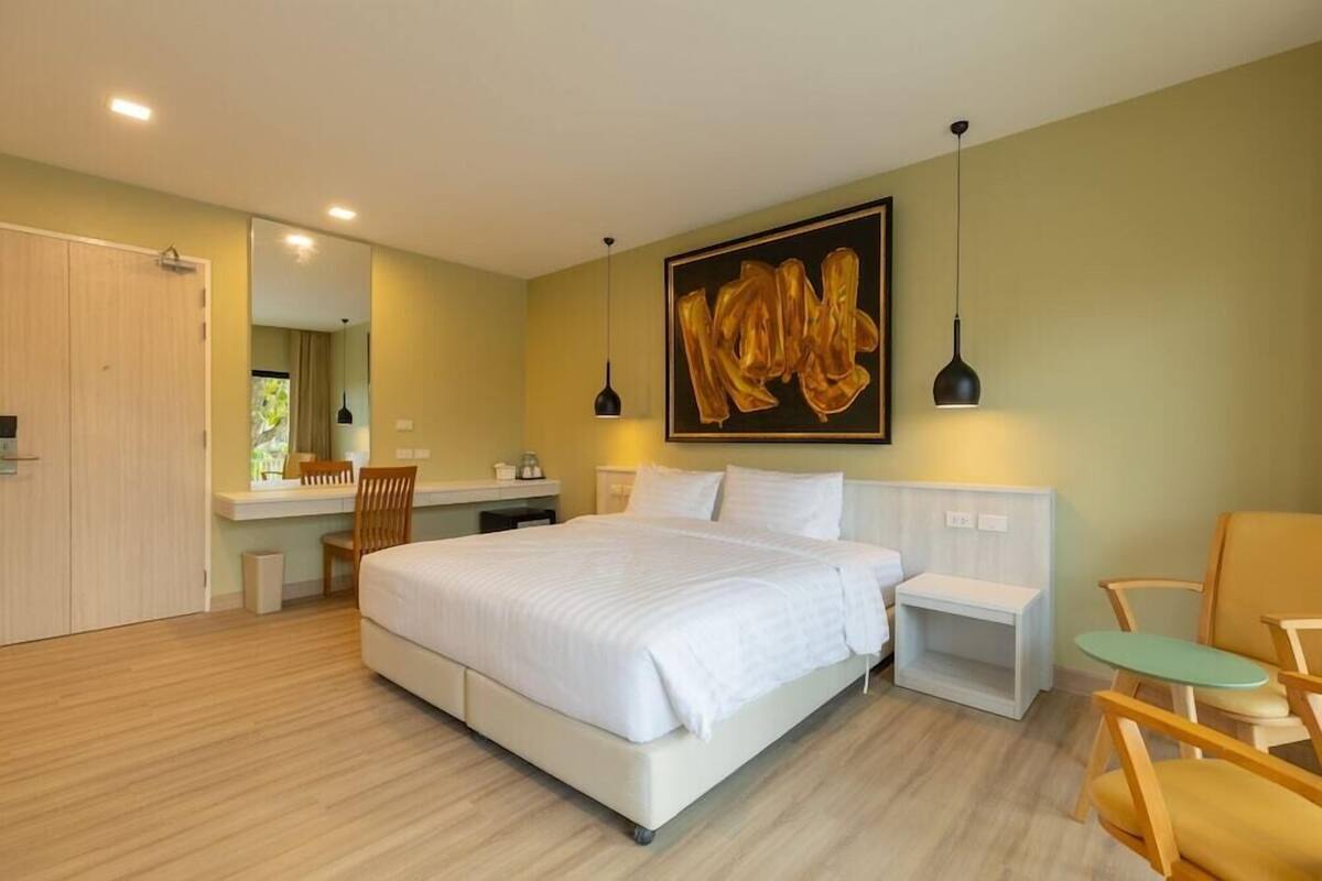 A modern bedroom with a large bed, bedside tables, a desk, and a chair.