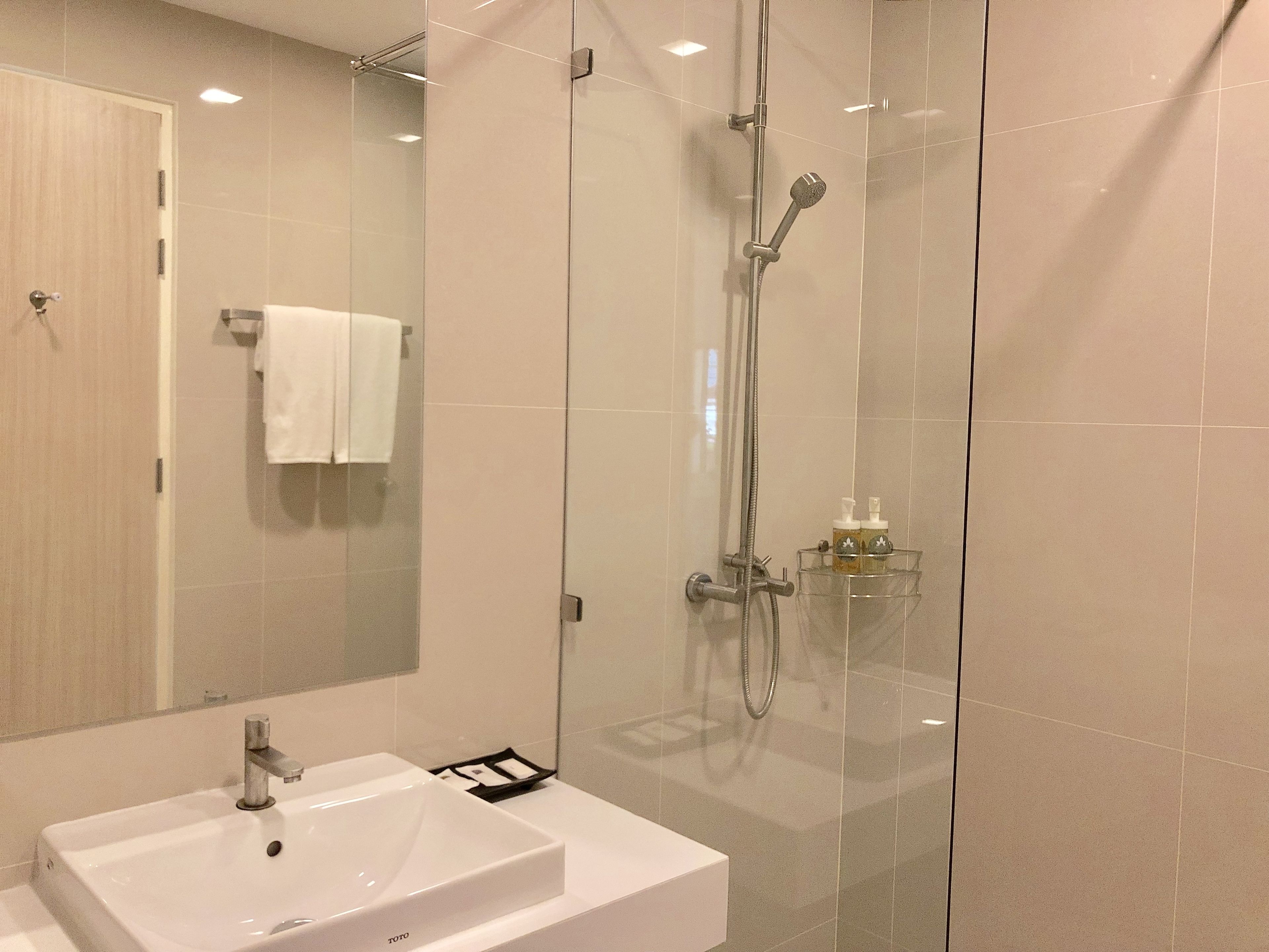 Une salle de bain moderne avec une douche à parois de verre, un lavabo blanc et un miroir.