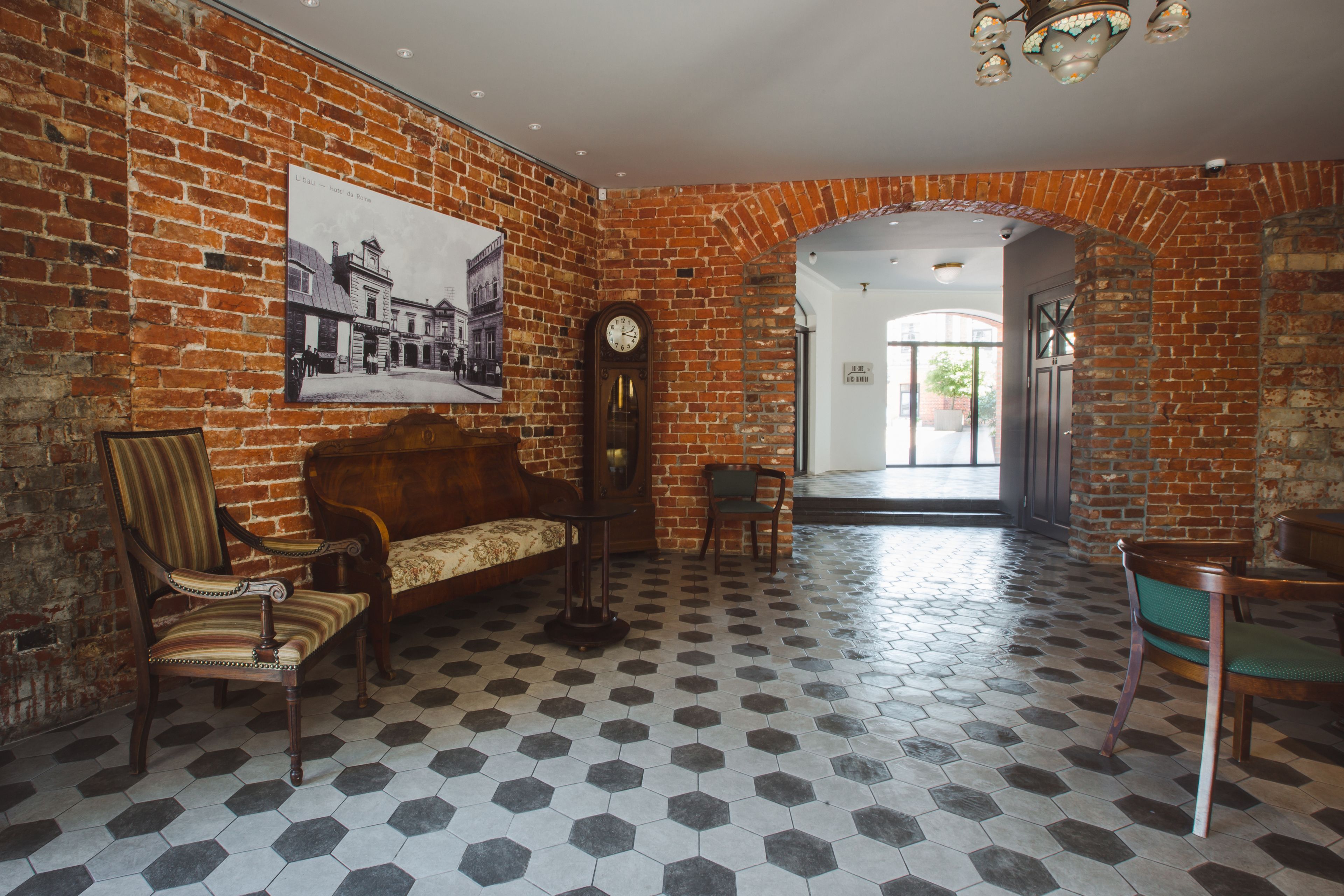 A room with a brick wall, a large clock, a sofa, and a patterned floor.
