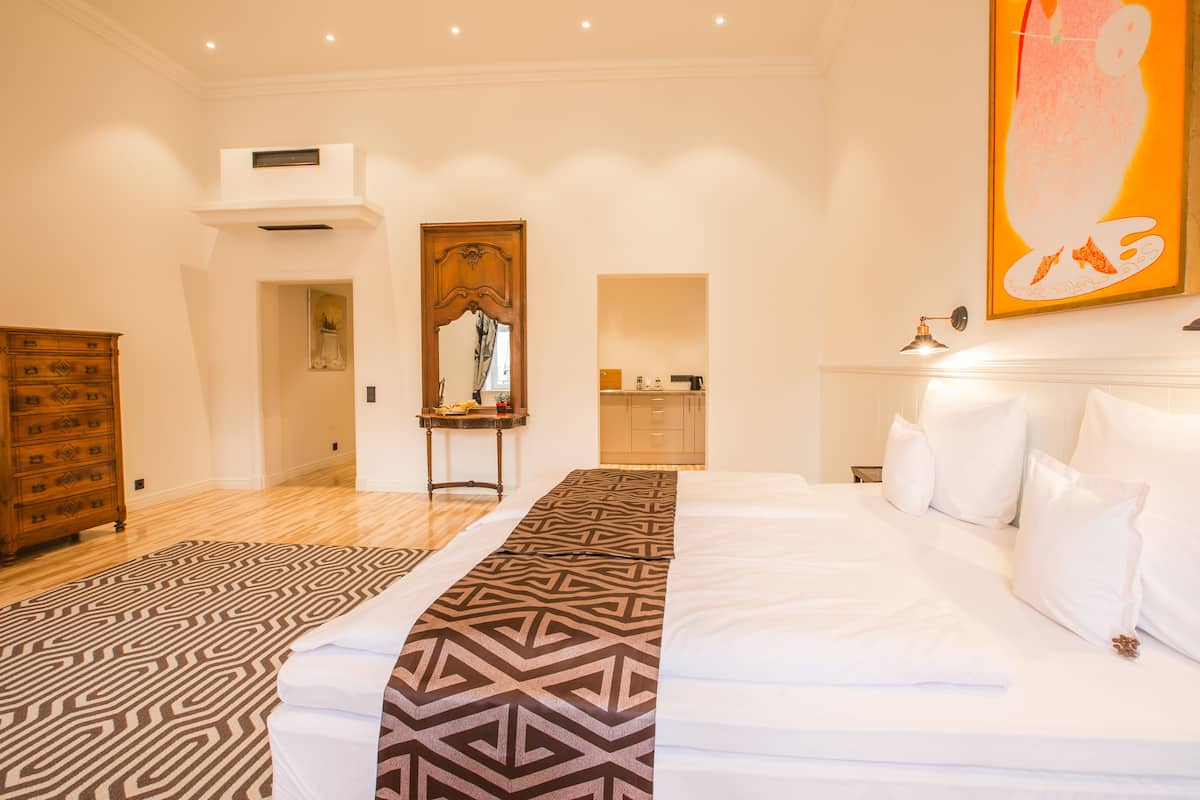 Una habitación de hotel con una cama grande, un aparador de madera, un espejo y un cuadro en la pared.