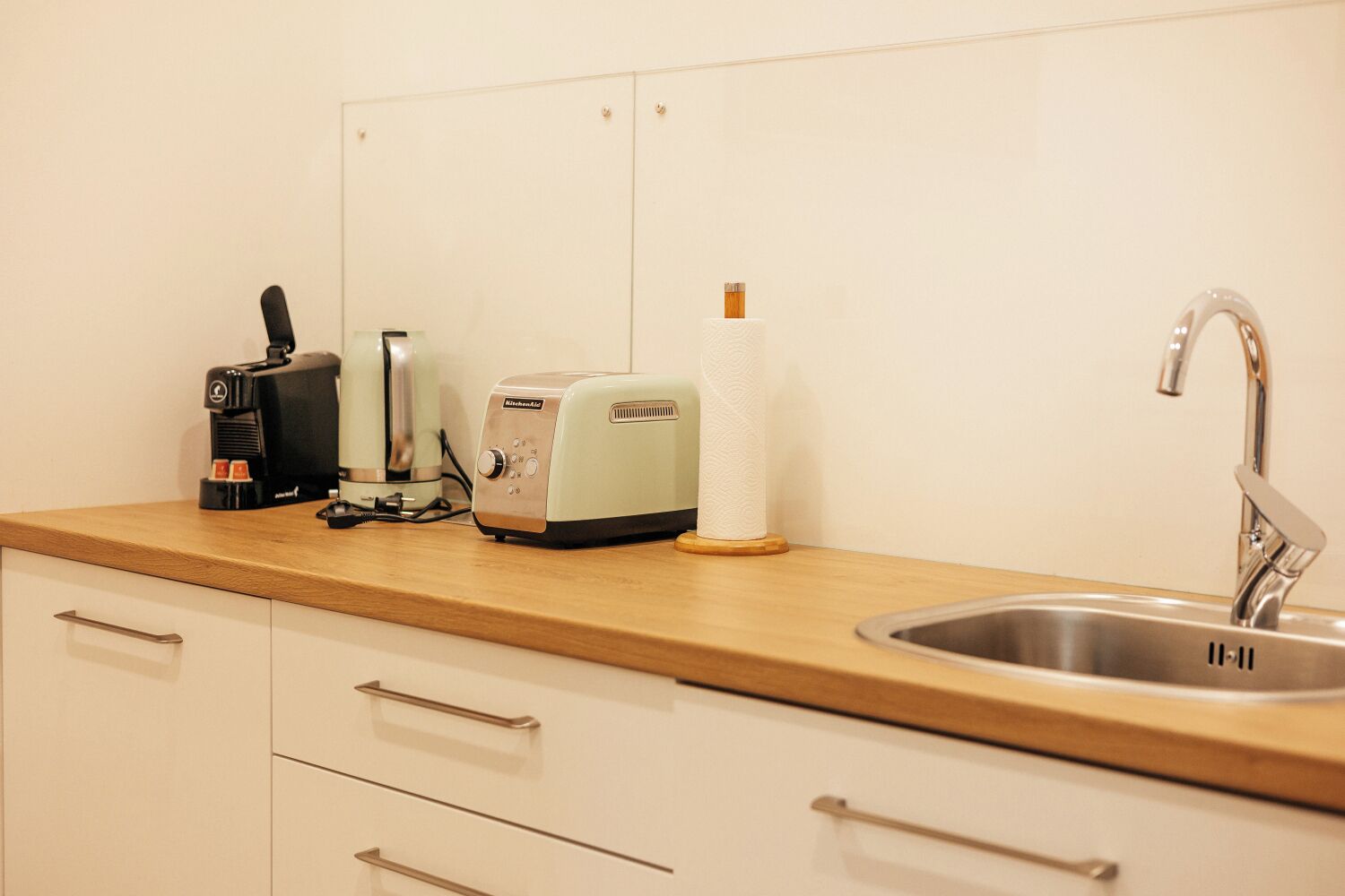 A kitchen with a wooden countertop, a coffee maker, a toaster, and a sink.