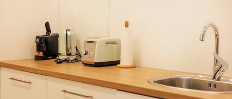 A kitchen with a wooden countertop, a coffee maker, a toaster, and a sink.