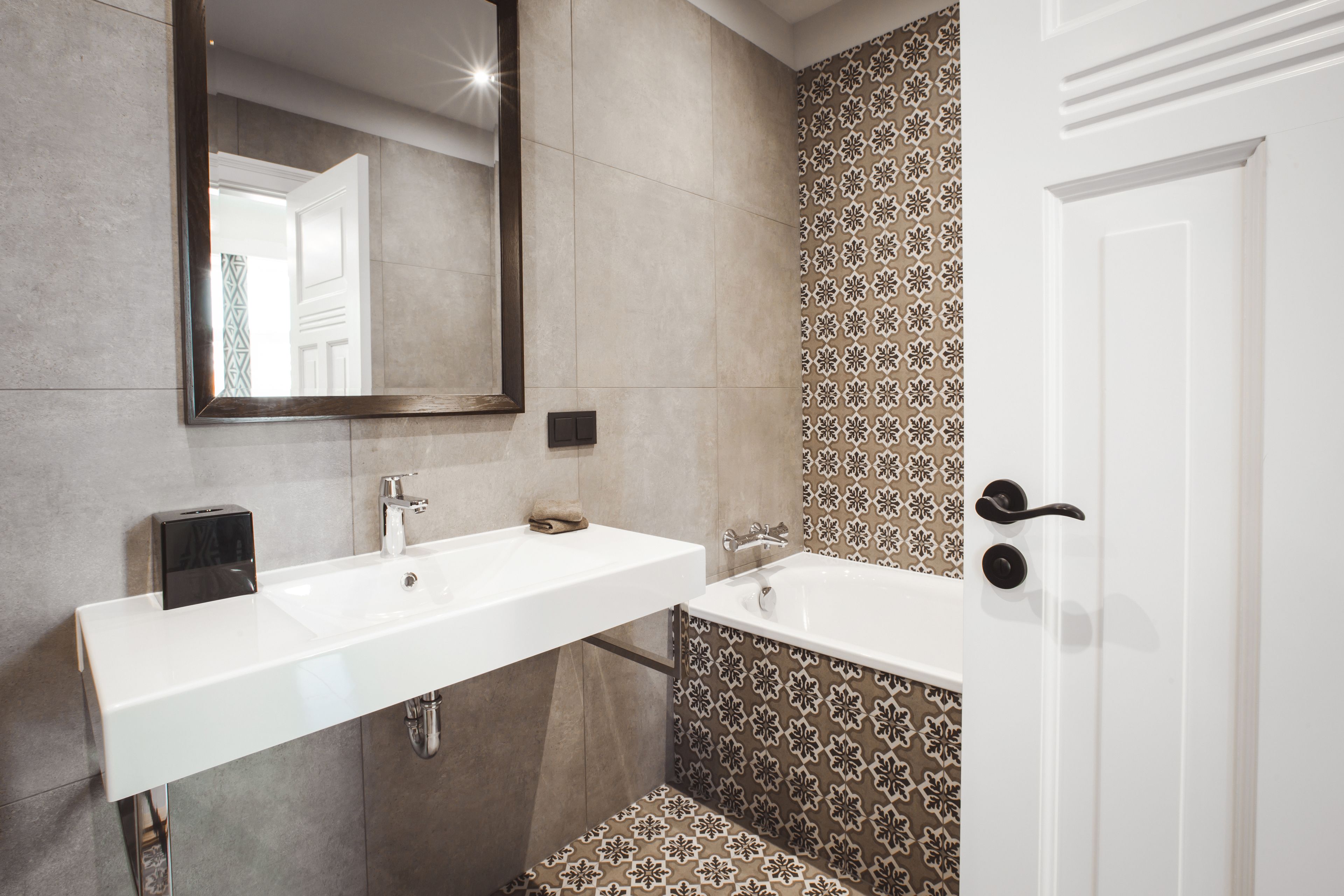 Un baño con lavamanos blanco, espejo y zona de ducha.