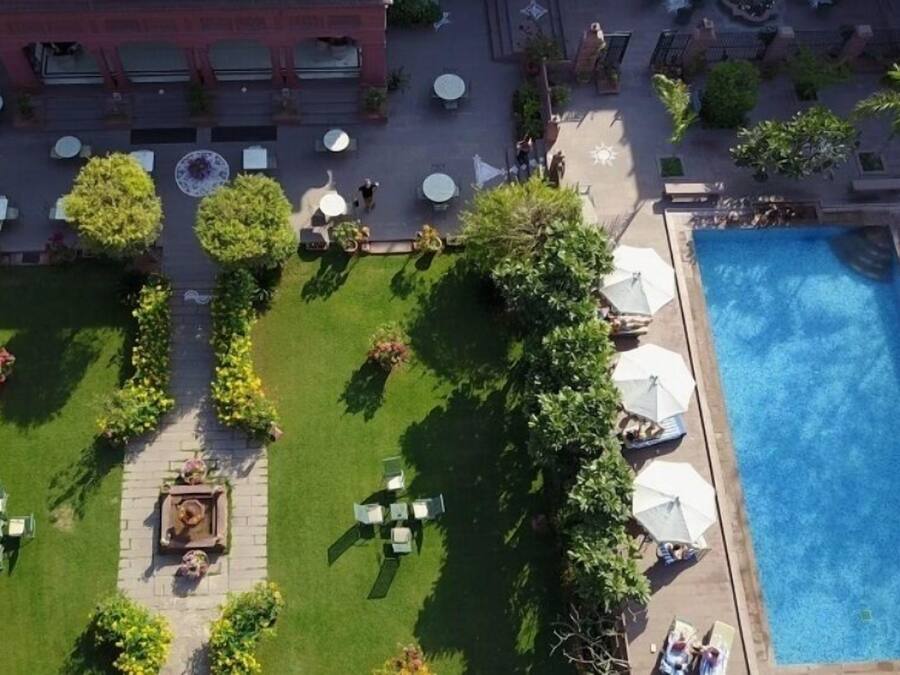 An aerial view of a hotel courtyard with a swimming pool, outdoor seating, and greenery.
