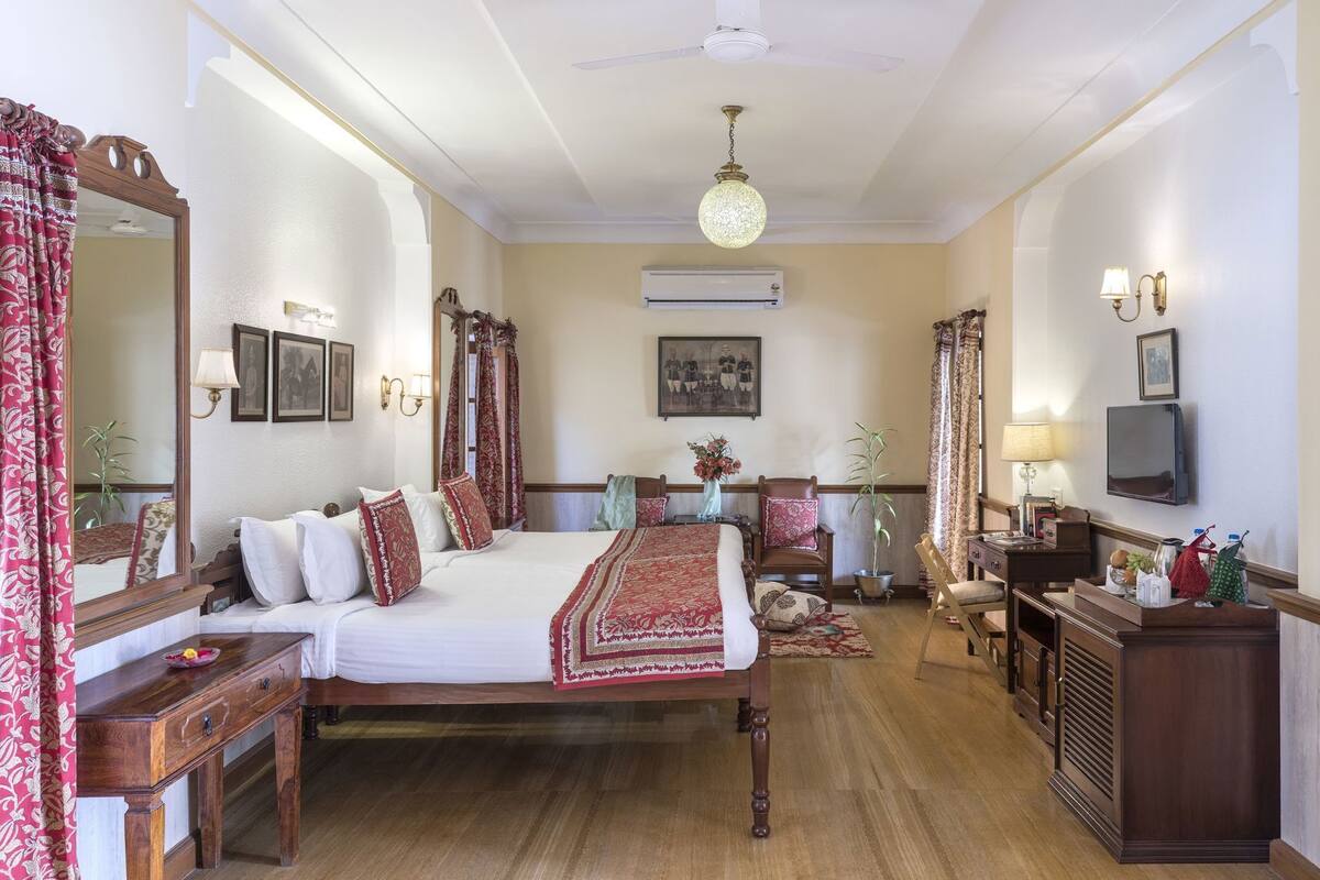 A traditional bedroom with a large bed, a wooden dresser, a television, and a ceiling fan.