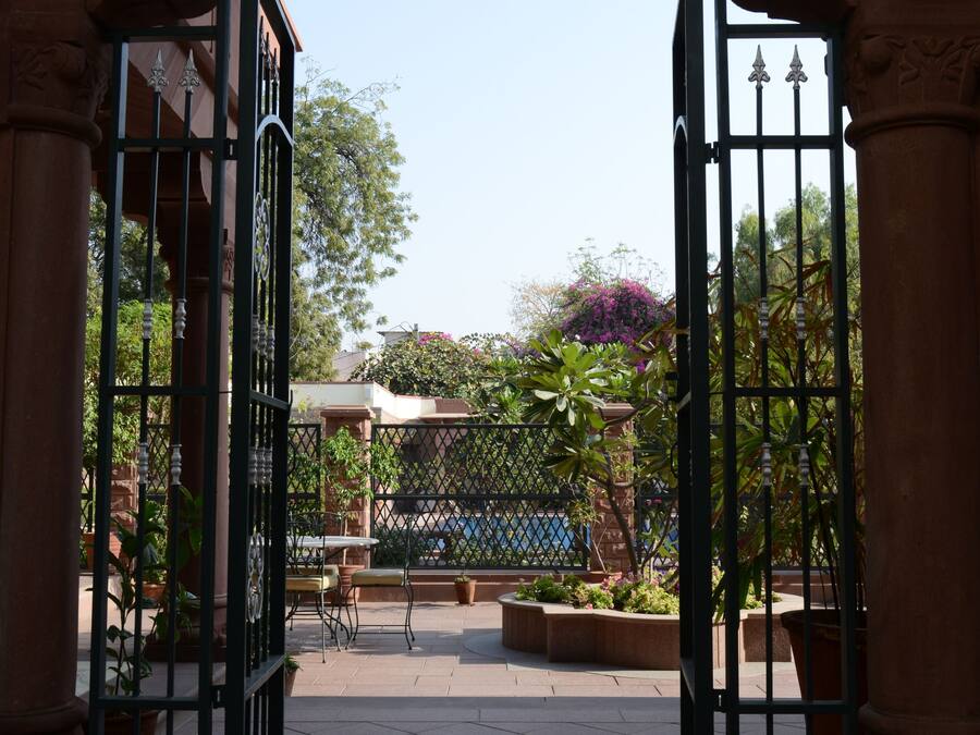 An open gate leading to a courtyard with a tiled floor and a decorative pattern.
