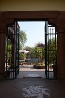 Een open poort die uitkomt op een binnentuin met betegelde vloer en decoratief patroon.