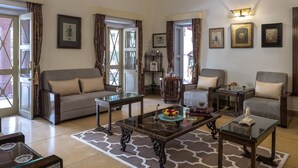 A spacious living room with a sofa, armchairs, a coffee table, and a chandelier.
