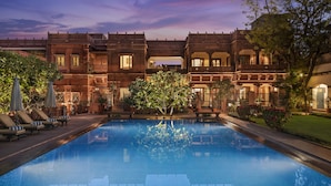 A pool area with lounge chairs and a large building with multiple balconies and windows.