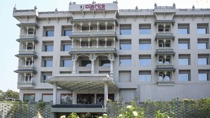 Ein mehrstöckiges Hotel mit Balkonen, einem überdachten Eingang und einem Schild mit der Aufschrift "Clarks Inn Suites".